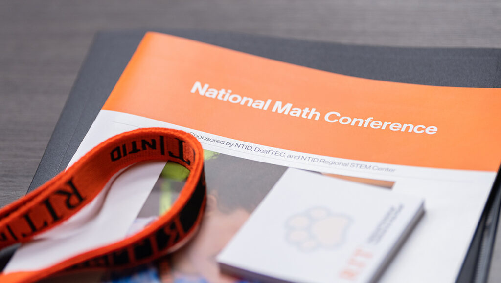Conference brochure with a lanyard and RIT Paw writing pad